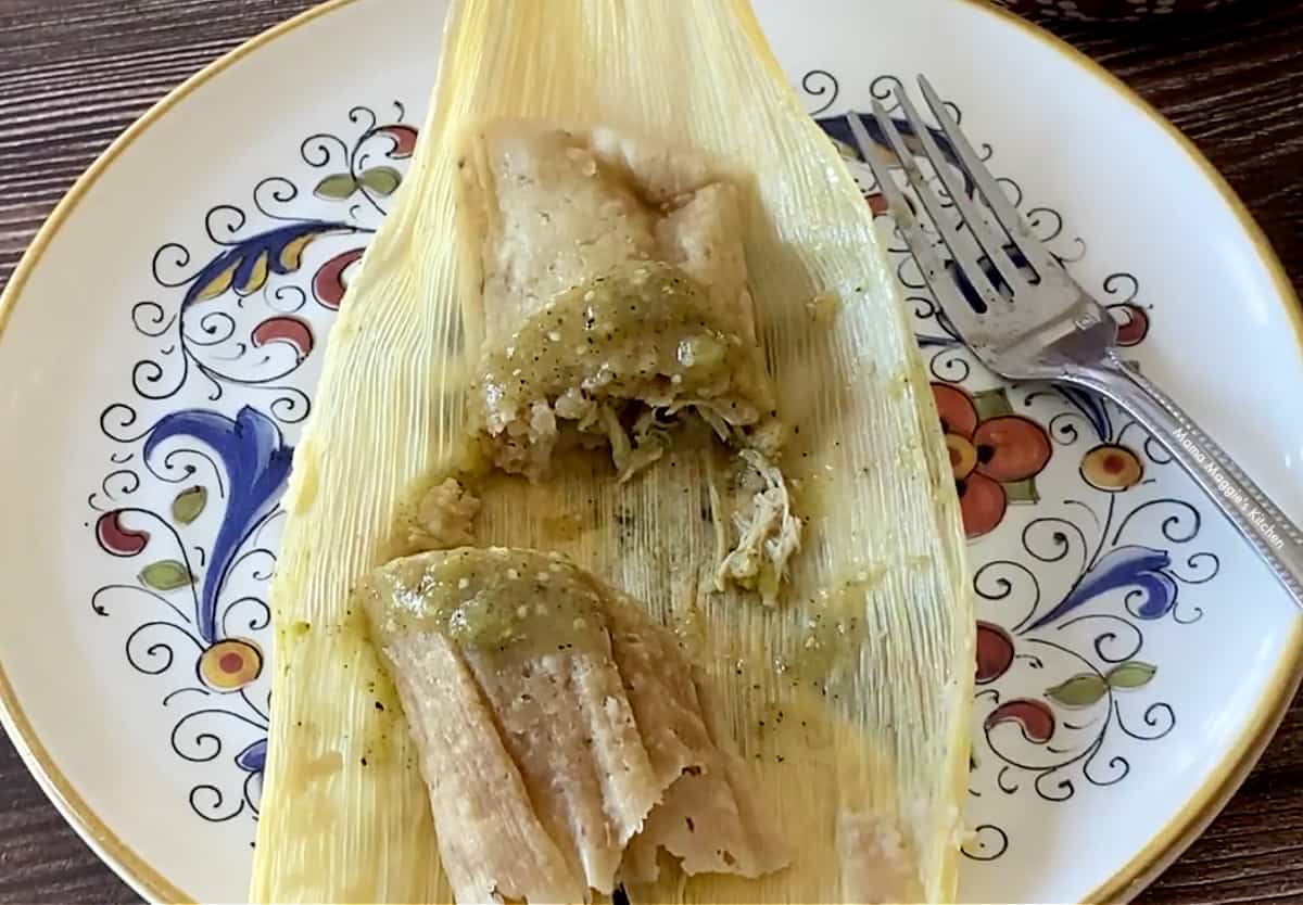 A chicken tamal cut in half and topped with salsa verde. 