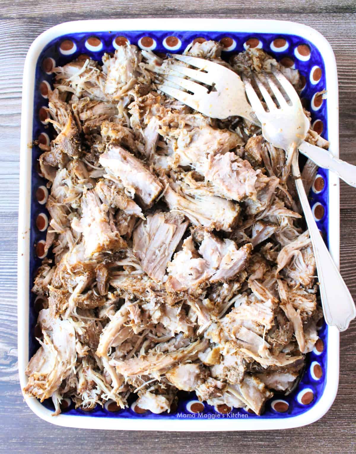Shredded pork on a plate next to two forks.