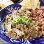 Slow Cooker Ancho Pork served on a blue plate and topped with jalapeno slices.