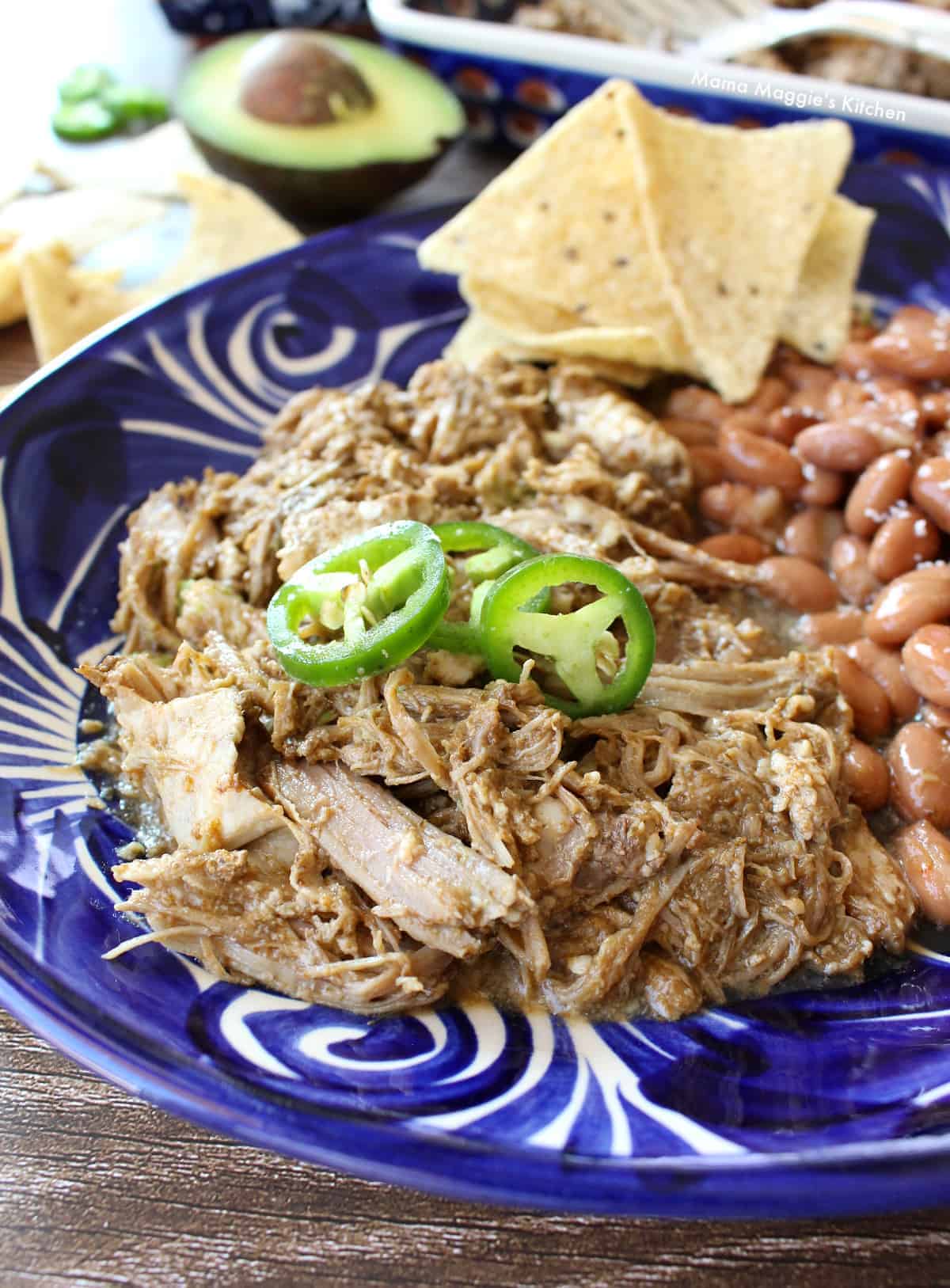 Slow Cooker Ancho Pork served on a blue plate and topped with jalapeno slices.