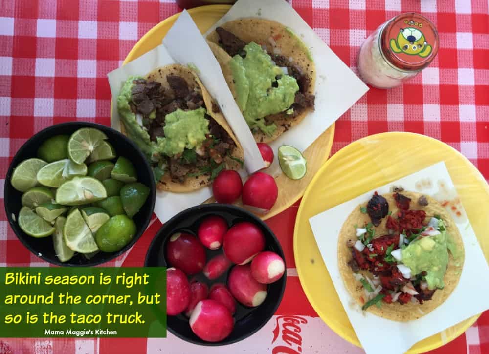 Tacos served next to radishes and lime on a checkered table.