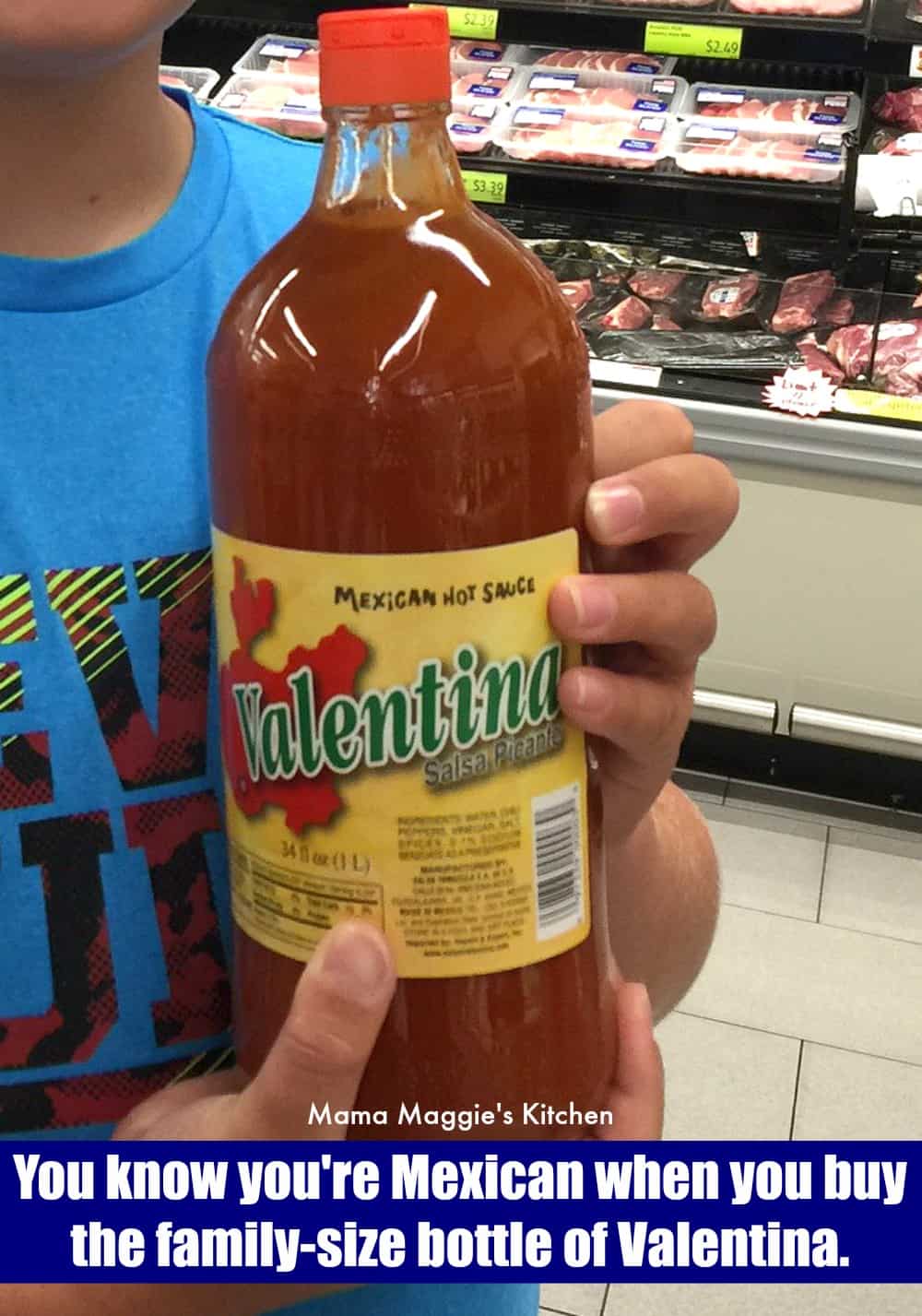 A hand holding a large bottle of Valentina hot sauce.