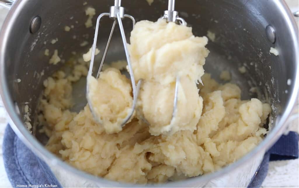The beaters of a hand mixer over raw dough.