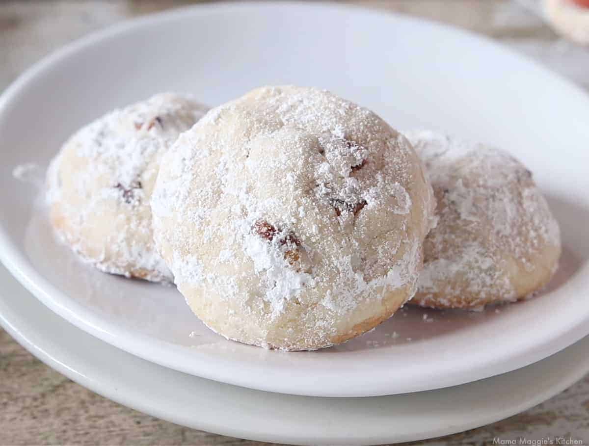 Three Mexican wedding cookies on a white plate.