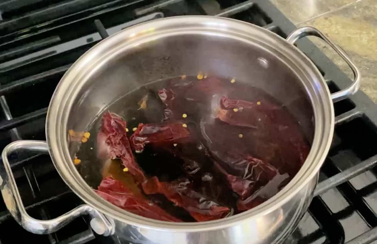 A stock pot boiling with guajillo chiles and water.