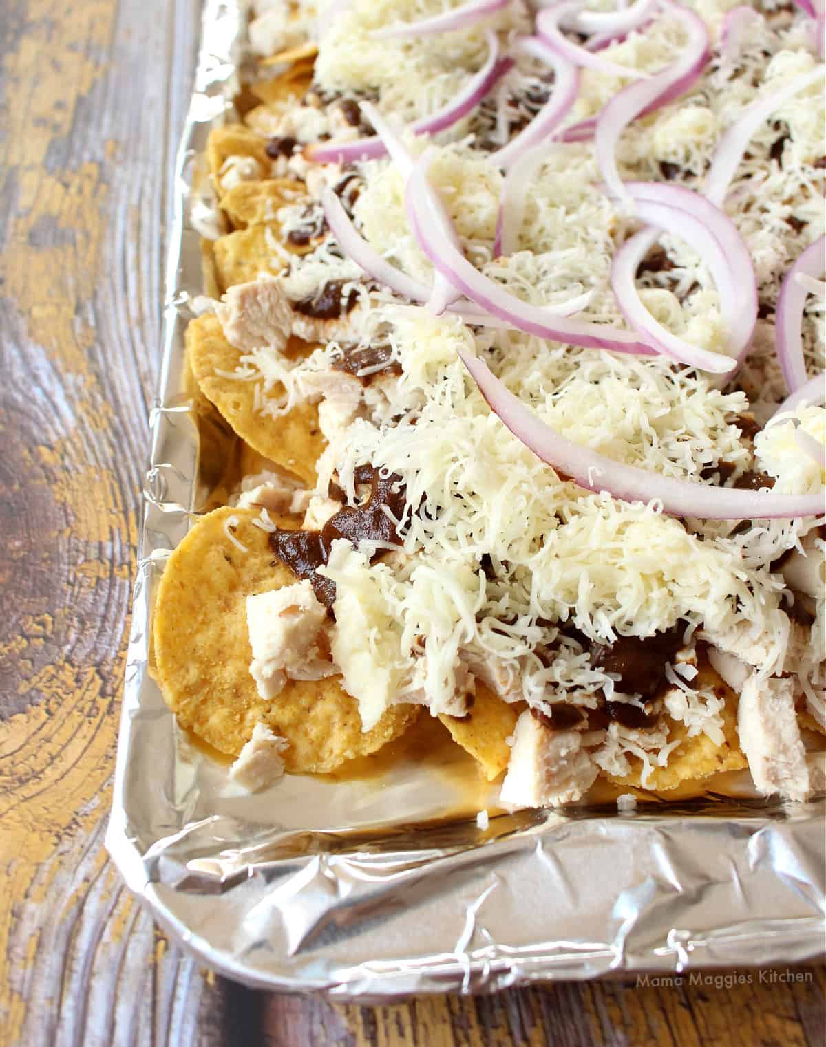 A sheet pan full of nachos ready to be placed in the oven.