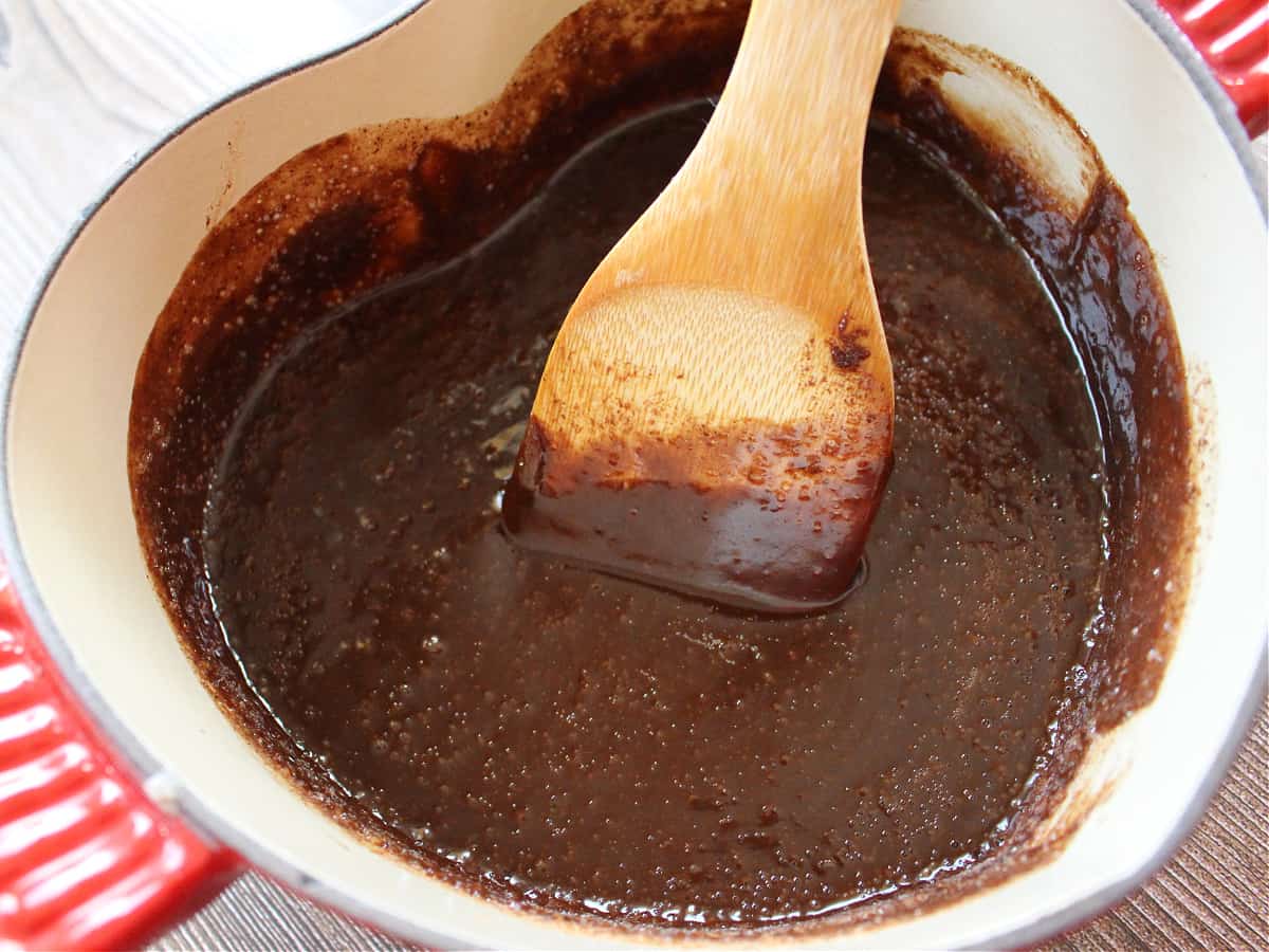 A wooden spoon stirring chocolate inside a pot.