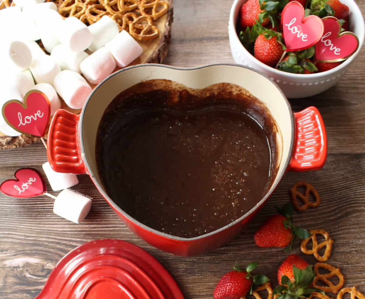 A heart-shaped pot with Mexican chocolate fondue surrounded by all the dipping items.
