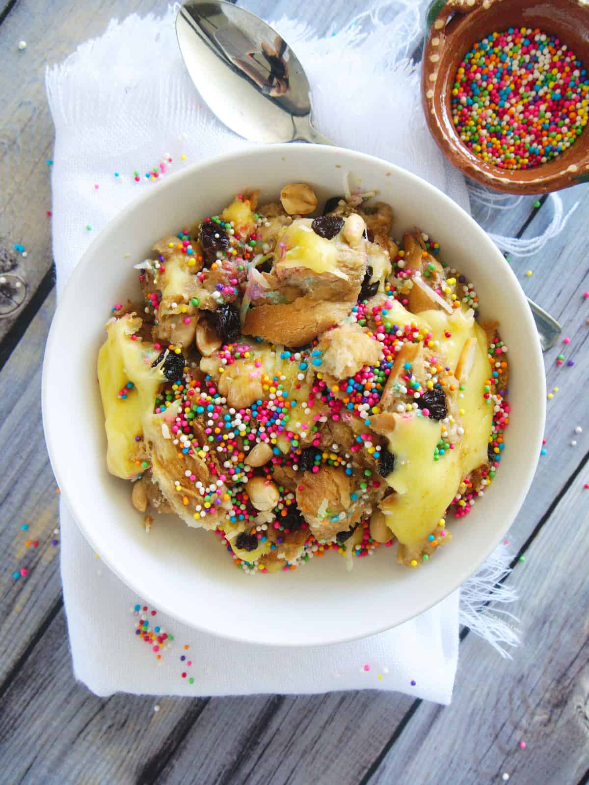Capirotada (or Mexican Bread Pudding) served in a white bowl and topped with sprinkles.