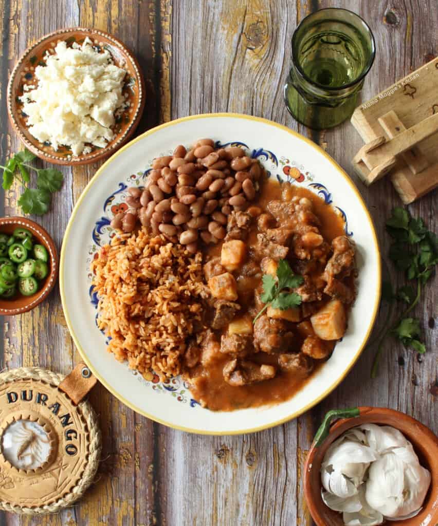 Carne con Papas served next to beans and rice and surrounded by toppings.