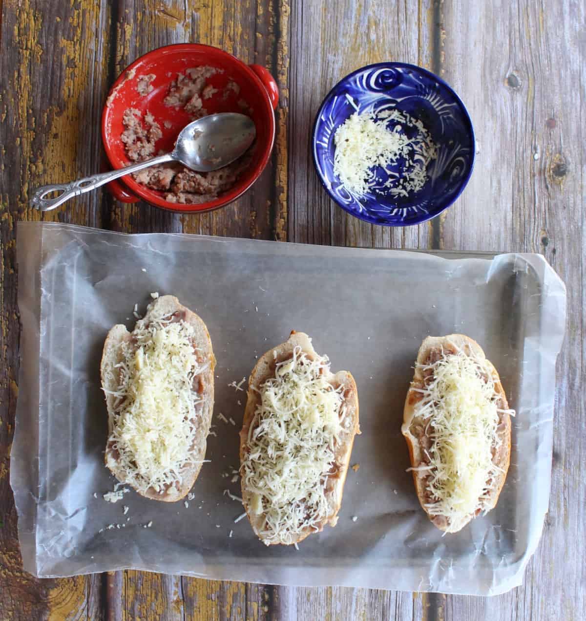 Three Mexican bolillos topped with cheese.