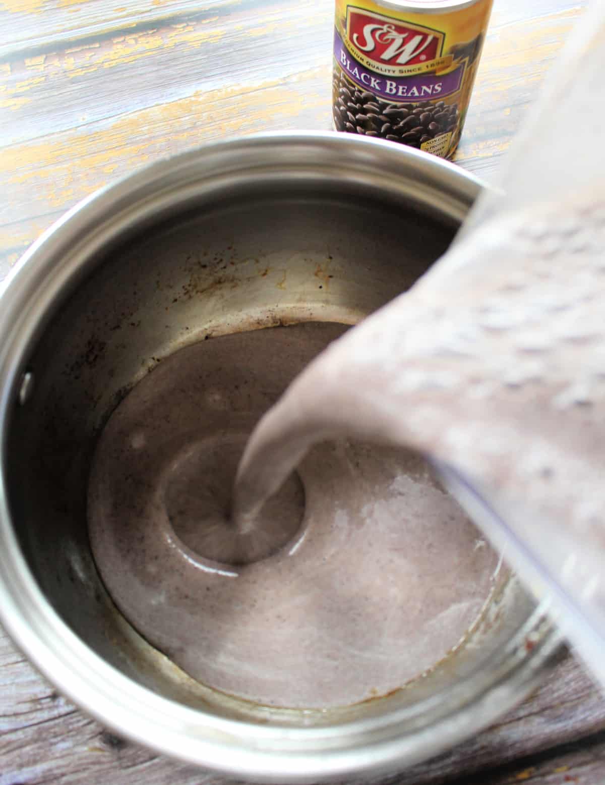 The bean soup pouring into a stock pot from the blender.
