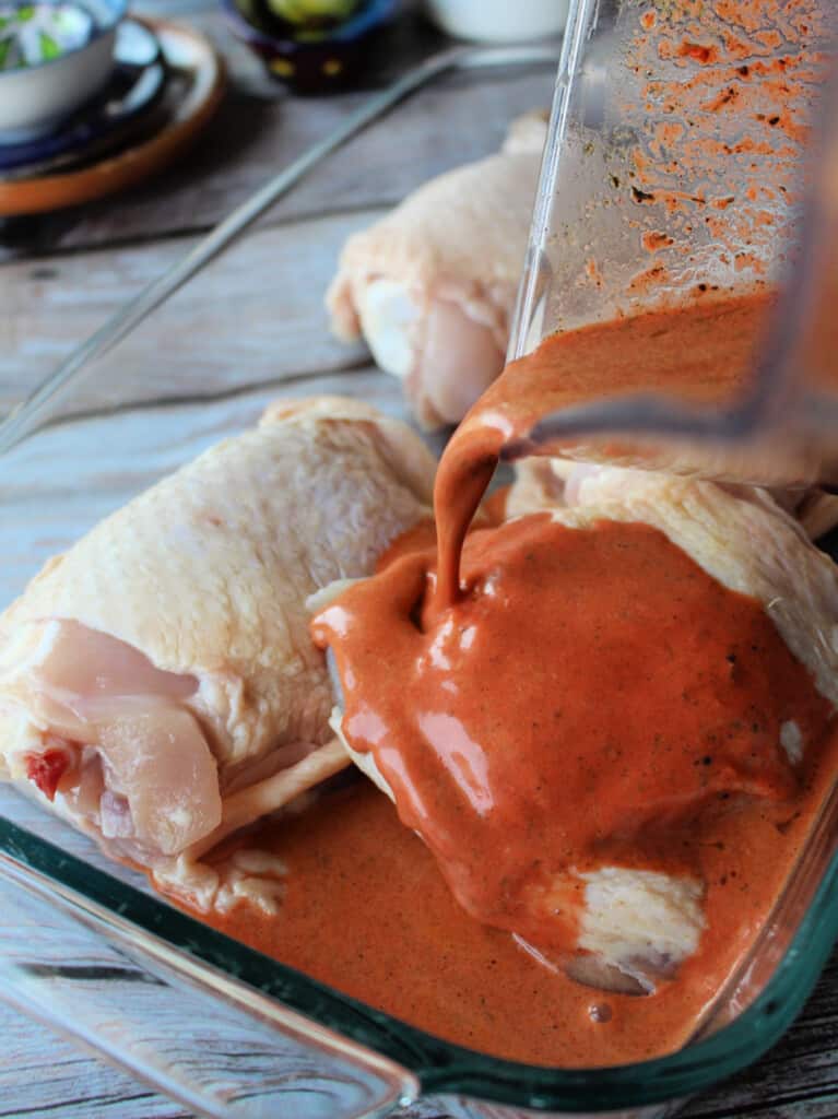 The achiote marinade pouring over raw chicken.