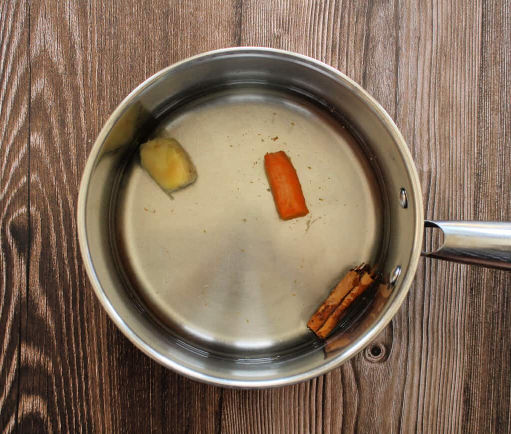 A pot with ginger, tumeric, and cinnamon stick.