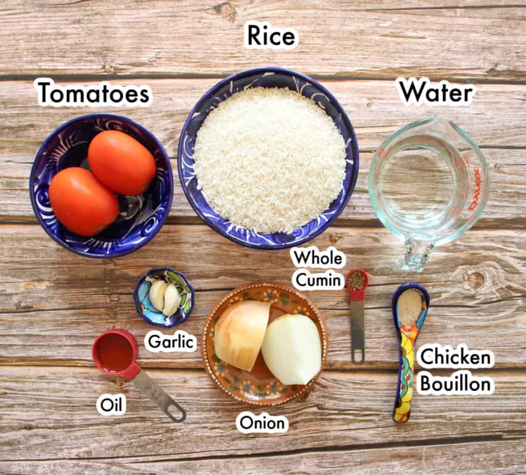 The ingredients needed to make Arroz Mexicano laid out and labeled on a wooden table.