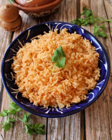 Arroz Mexicano (or Mexican Rice) served in a decorative blue plate and topped with a cilantro leaf.