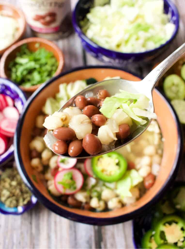 A spoon of bean pozole over the bowl.