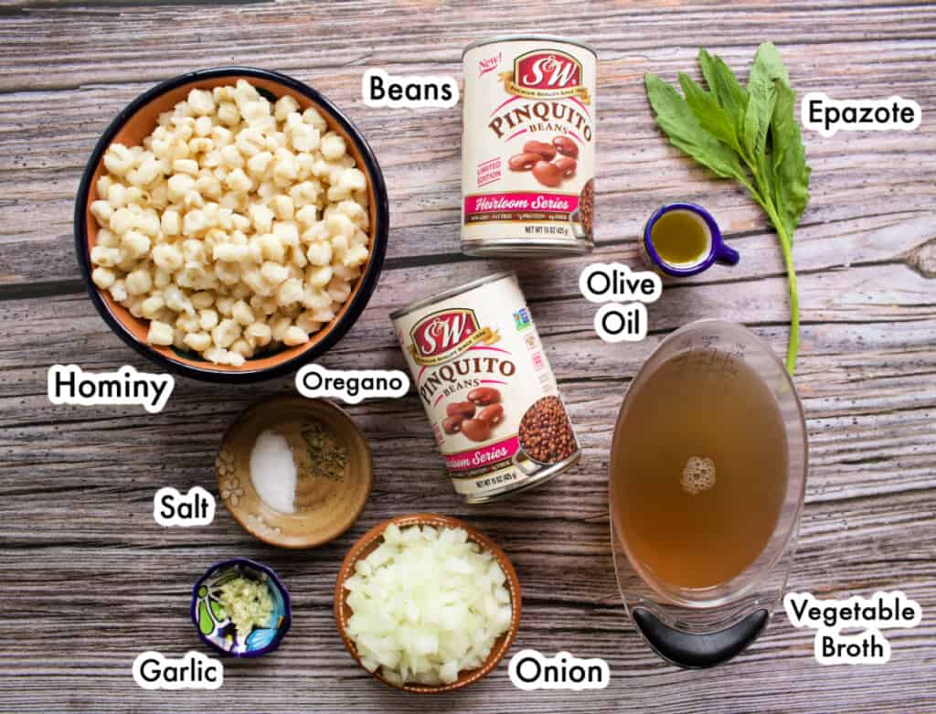 The ingredients needed to make pozole de frijol on a wooden surface and labeled.