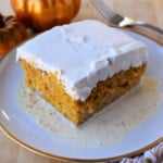 A slice of Pumpkin Pastel de Tres Leches served on a plate and topped with whipped cream.