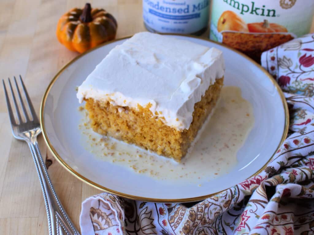 A slice of Pumpkin Pastel de Tres Leches served on a plate and topped with whipped cream.