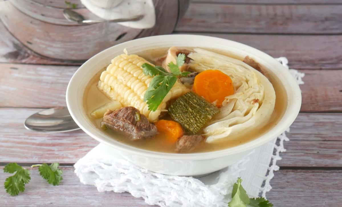 Caldo de Res served in a white bowl and loaded with hearty vegetables.