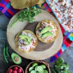Two Shrimp Ceviche tostadas topped with avocado and surrounded by potential toppings.