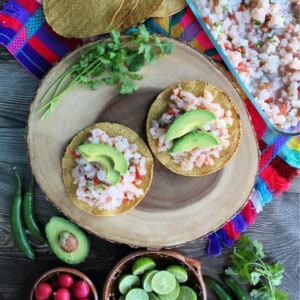 Two Shrimp Ceviche tostadas topped with avocado and surrounded by potential toppings.