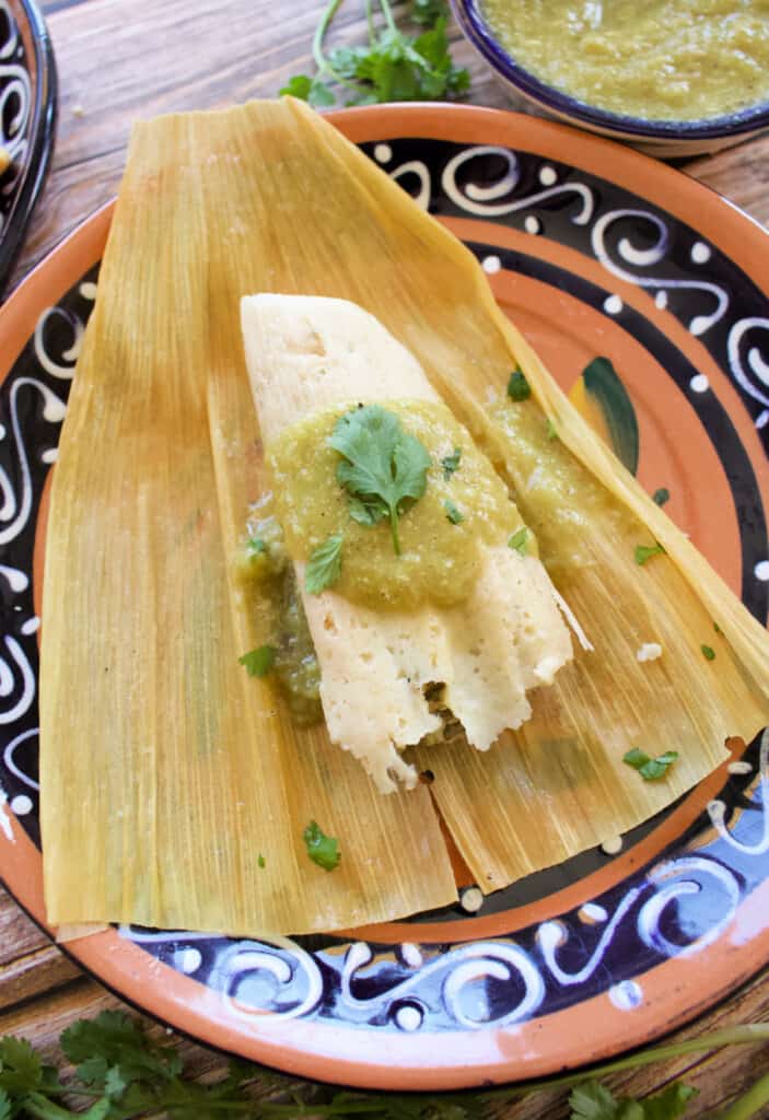 A tamal unwrapped and sitting on a cork husk.