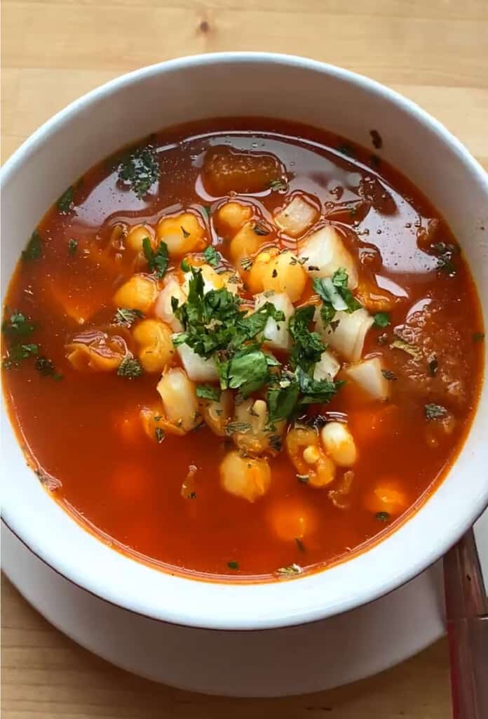 Mexican Menudo tripe soup served in a white bowl and topped with cilantro.