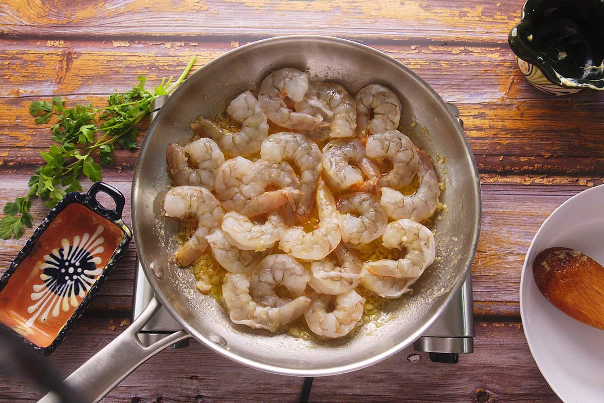 Shrimp cooked in a sauce of melted butter, garlic and pepper in a pan on the stove