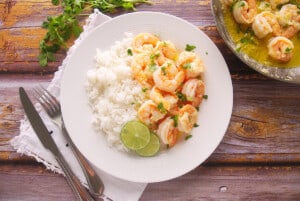 Shrimp and rice served in a glass plate with lime slices as garnish
