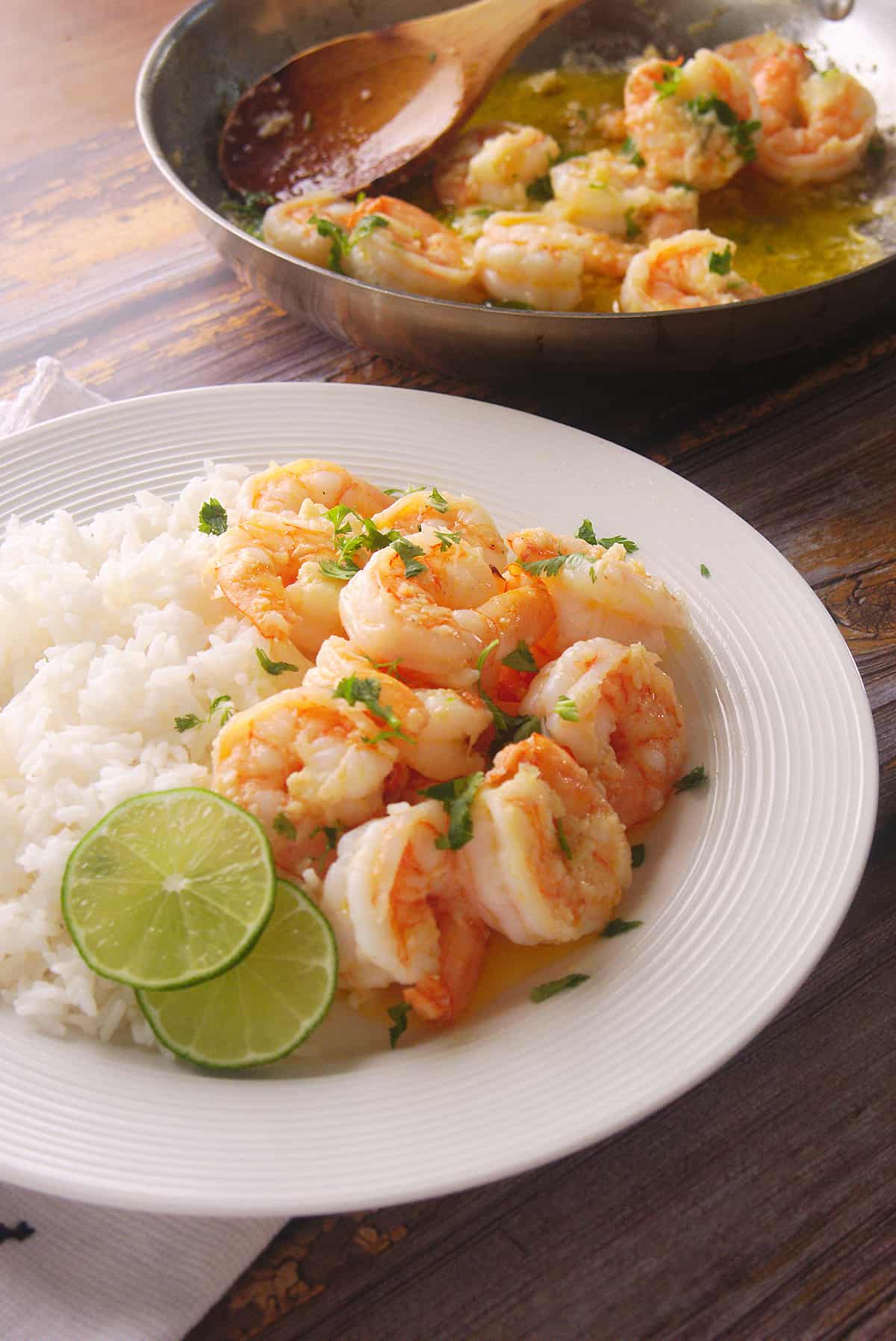 Shrimp and rice served in a glass plate with lime slices as garnish