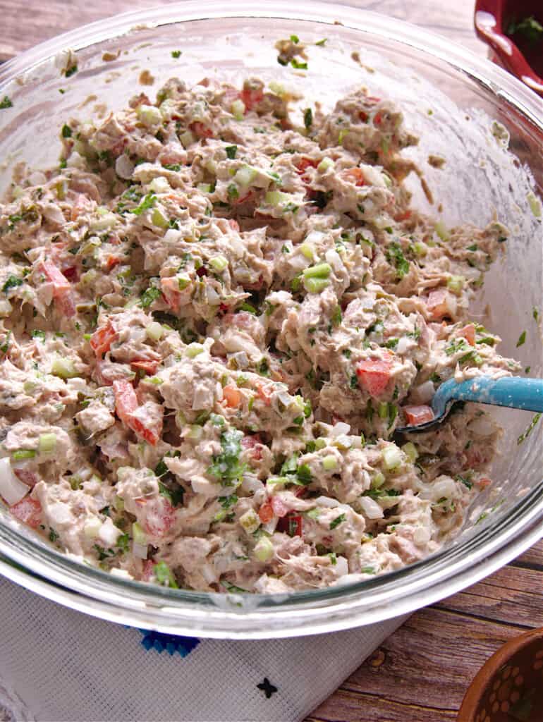 Ensalada de Atún (or Mexican Tuna Salad) mixed with the mayo and in a glass bowl with a cooking spoon.