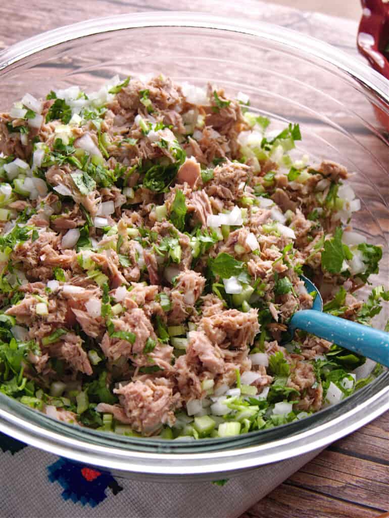 A glass bowl filled with tuna, onion, and cilantro.