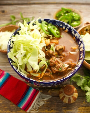 Red Beef Pozole served in a decorative blue bowl and topped with cabbage.