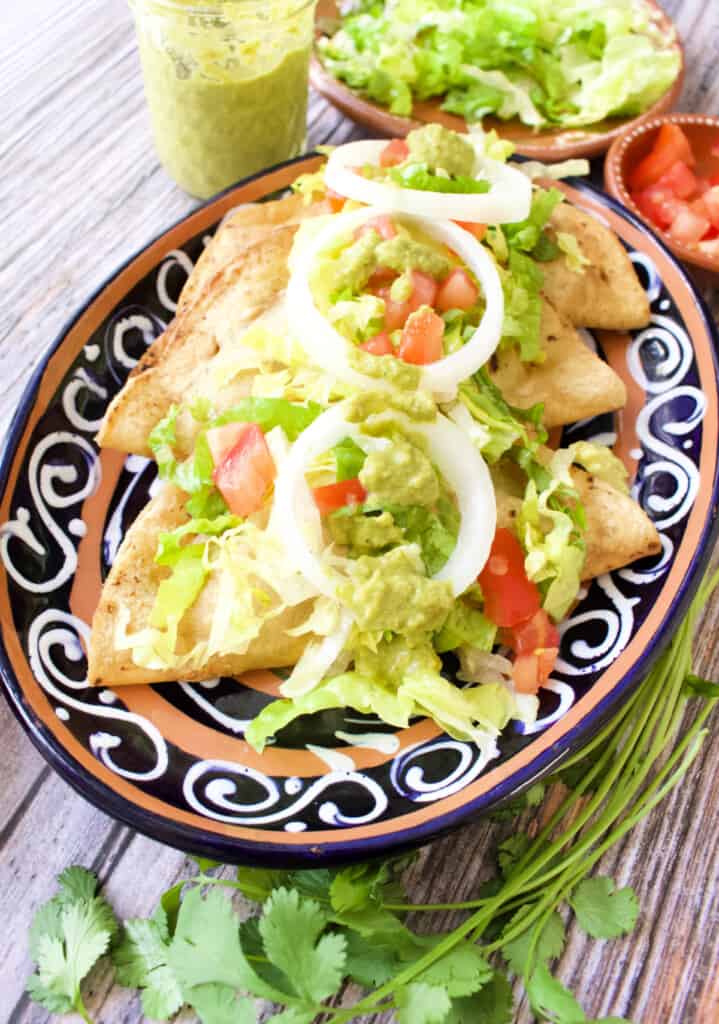 Bean Tacos Dorados served and topped with lettuce, tomatoes, and more.