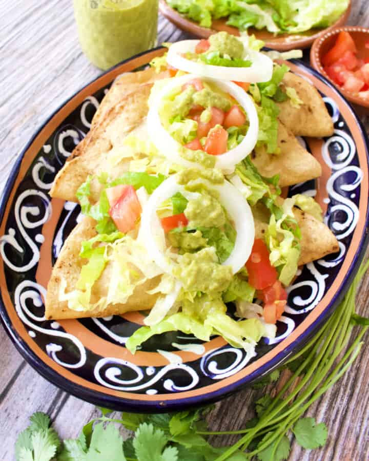 Bean Tacos Dorados served and topped with lettuce, tomatoes, and more.