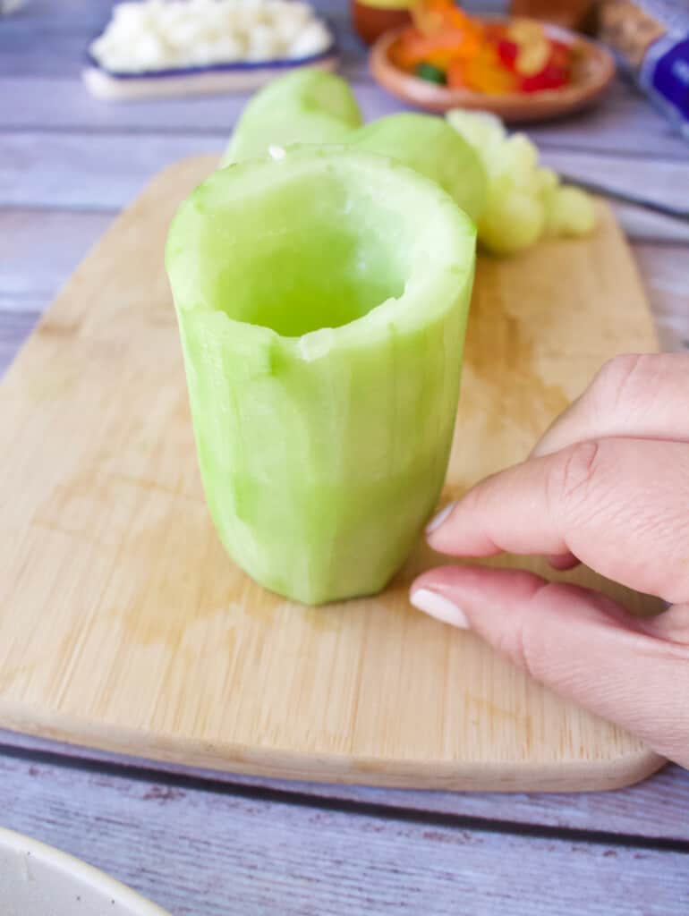 A hand showing how much of the inside of the cucumber to remove.
