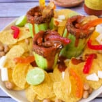 A serving platter with pepinos locos, corn chips, lime, and more.