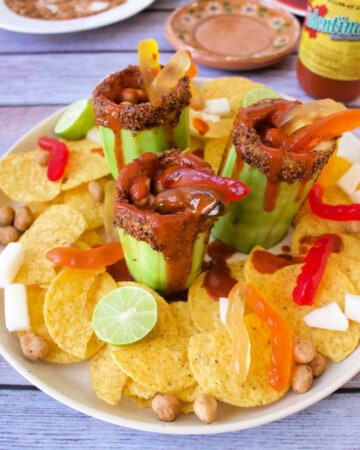 A serving platter with pepinos locos, corn chips, lime, and more.