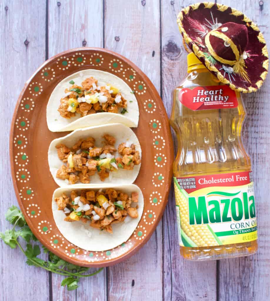 A picture of al pastor tacos next to a bottle of Mazola corn oil.