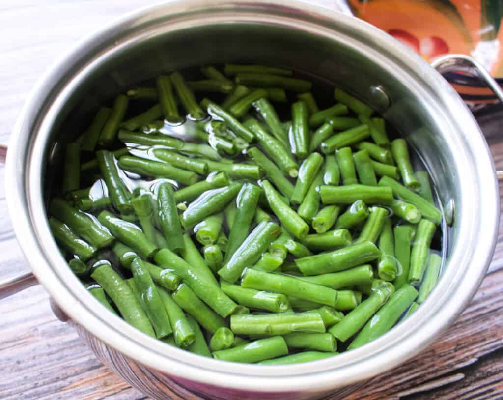 Green beans cooking in a water in a stock pot.