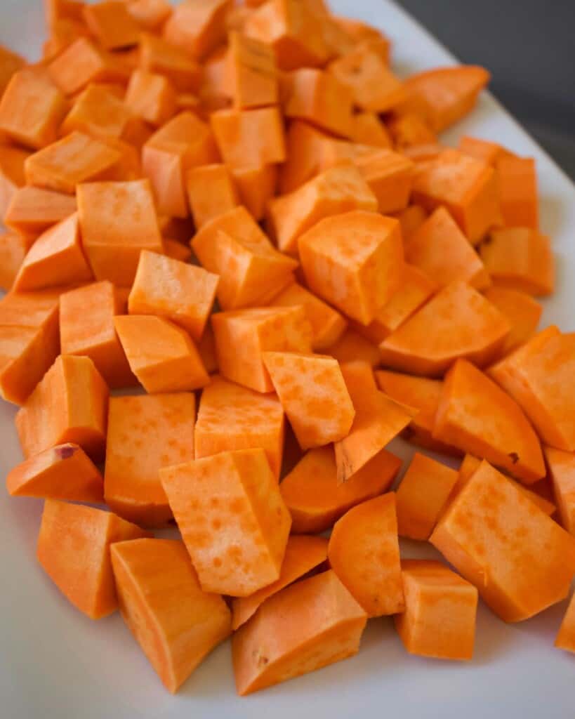 Diced sweet potatoes sitting on a white plate.