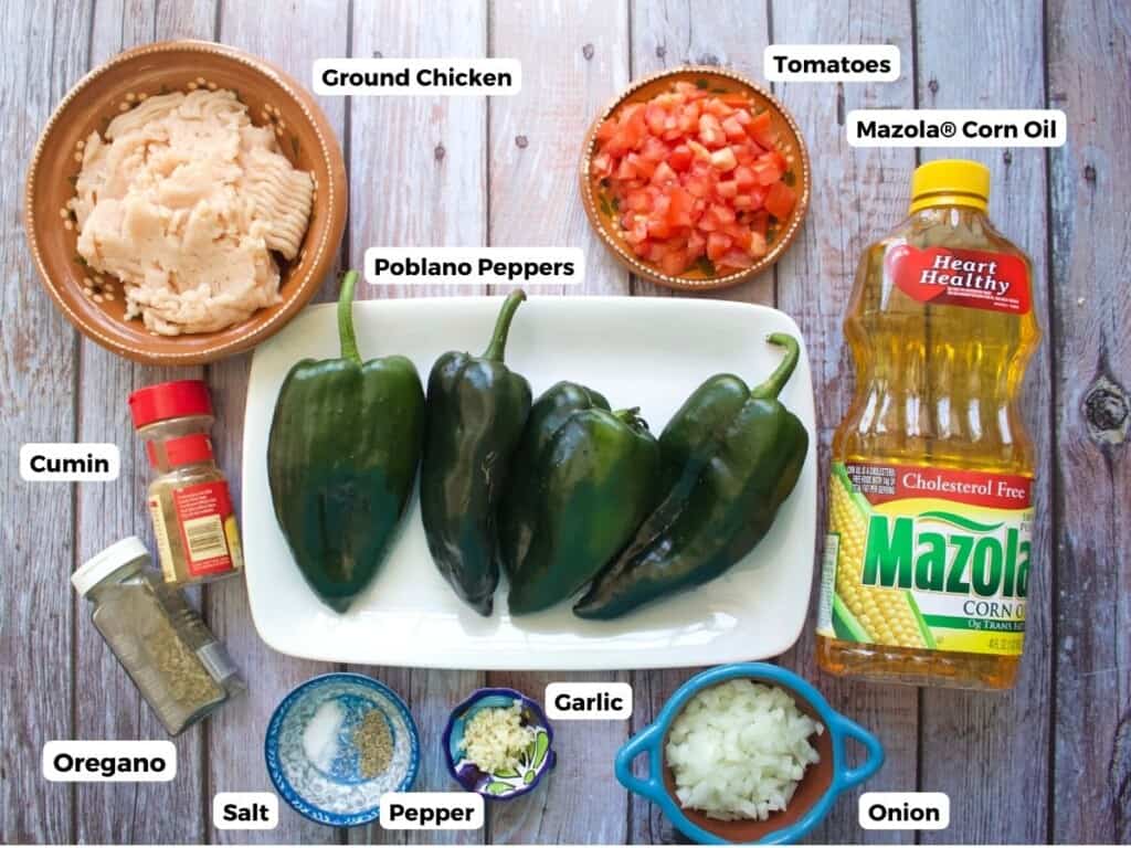 The ingredients needed to make chicken chile rellenos labeled and sitting on a wooden surface.