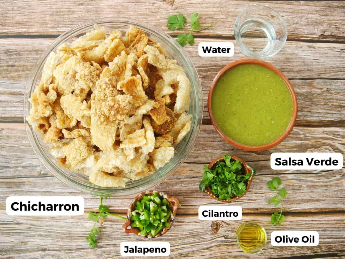 The ingredients needed to make chicharron en salsa verde labeled and sitting on a wooden surface.