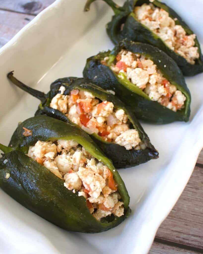 Stuffed poblano peppers sitting in a white casserole dish.