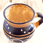 A cup of atole de elote dusted off with ground cinnamon.