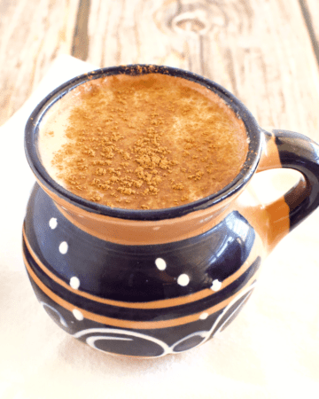 A cup of atole de elote dusted off with ground cinnamon.