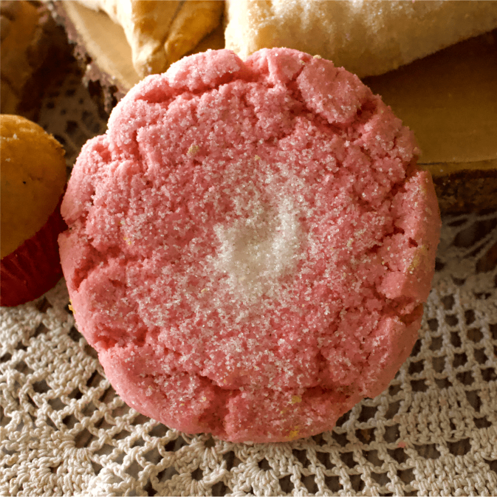 A pink polvorones cookie sitting on a knitted napkin.