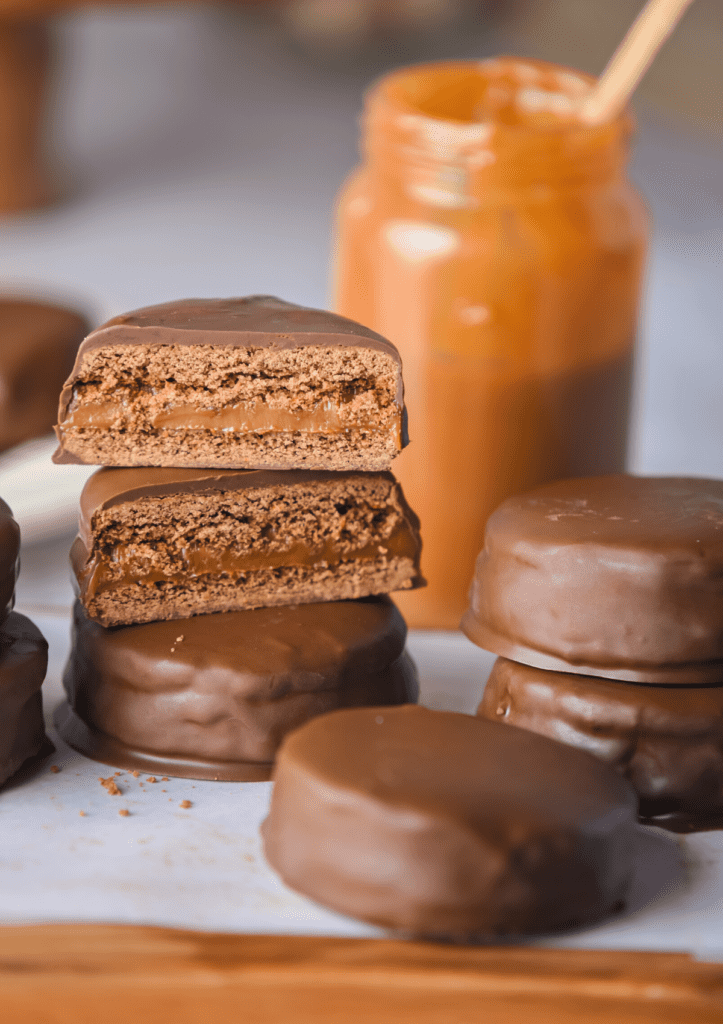 Chocolate Argentinian Alfajores piled on top of each other and two are cut in half.